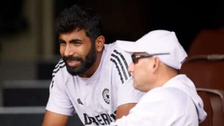Jasprit Bumrah seated in Team India training gear in discussion with team support staff during a fitness assessment session.